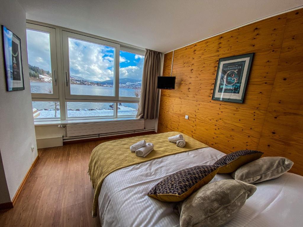 a bedroom with a large bed with a large window at Appart'Hôtel LIDO au bord de l'eau in Gérardmer