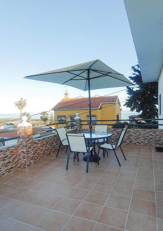 stół i krzesła z parasolem na patio w obiekcie Villa del Carmen w mieście Almayate Alto