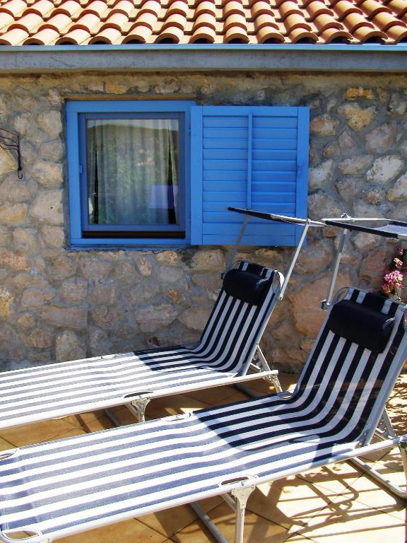 two chairs sitting in front of a building with a window at Charming dalmatian apartment with panoramic view in Tkon