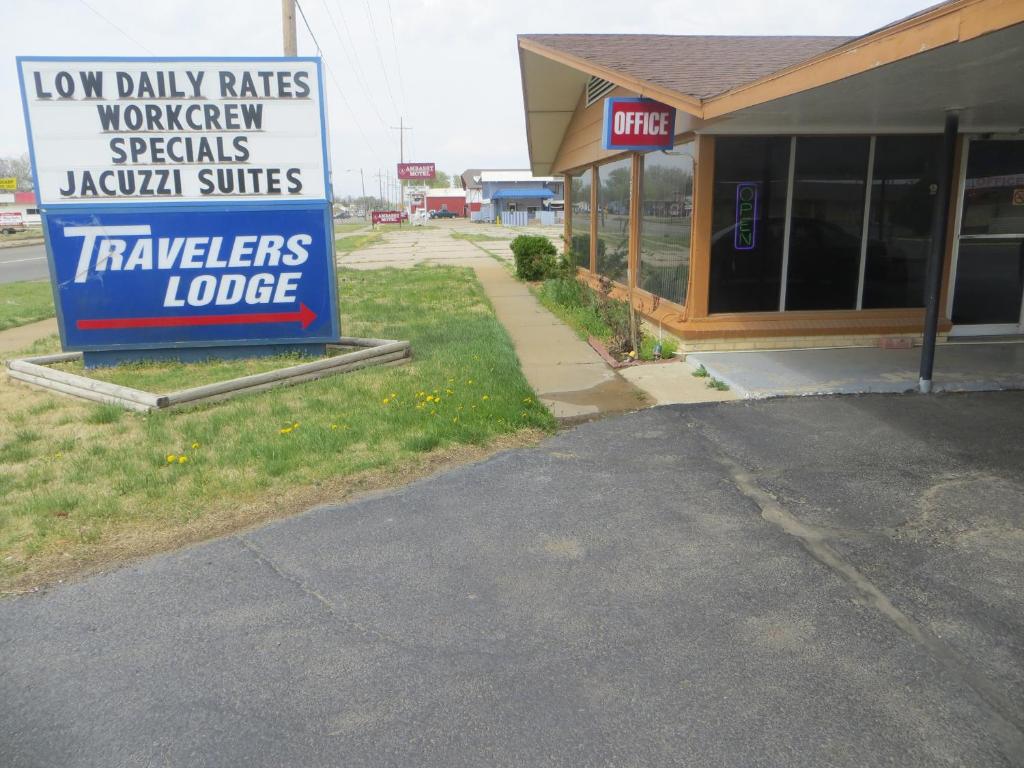 a store with a sign for a car dealership at Traveler's Lodge in Salina