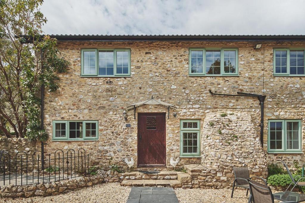 a stone house with a wooden door and windows at Blackdown Cottage in Stockland