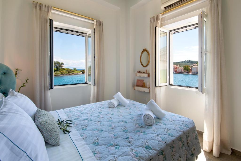 a bedroom with a bed with two large windows at Sea Front Suite "SEA TALES" in Gaios