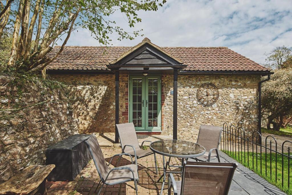 a patio with a table and chairs in front of a building at Harcombe Cottage in Stockland