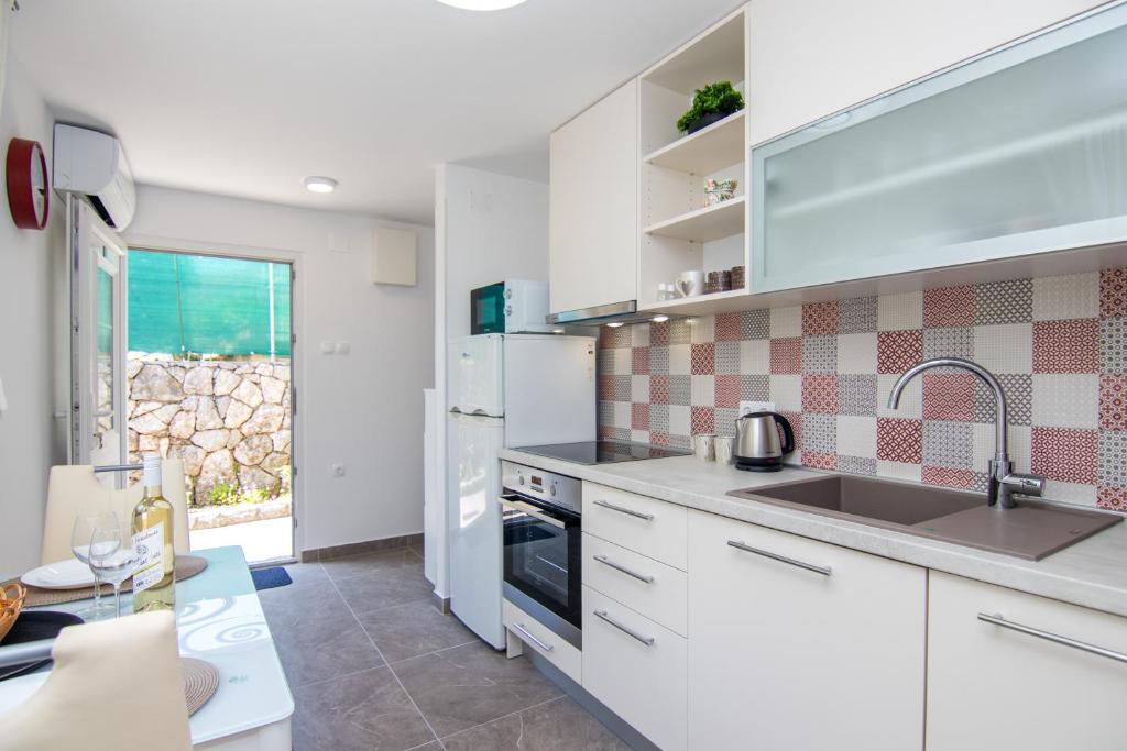uma cozinha com armários brancos e um lavatório em Apartman Mara em Krk