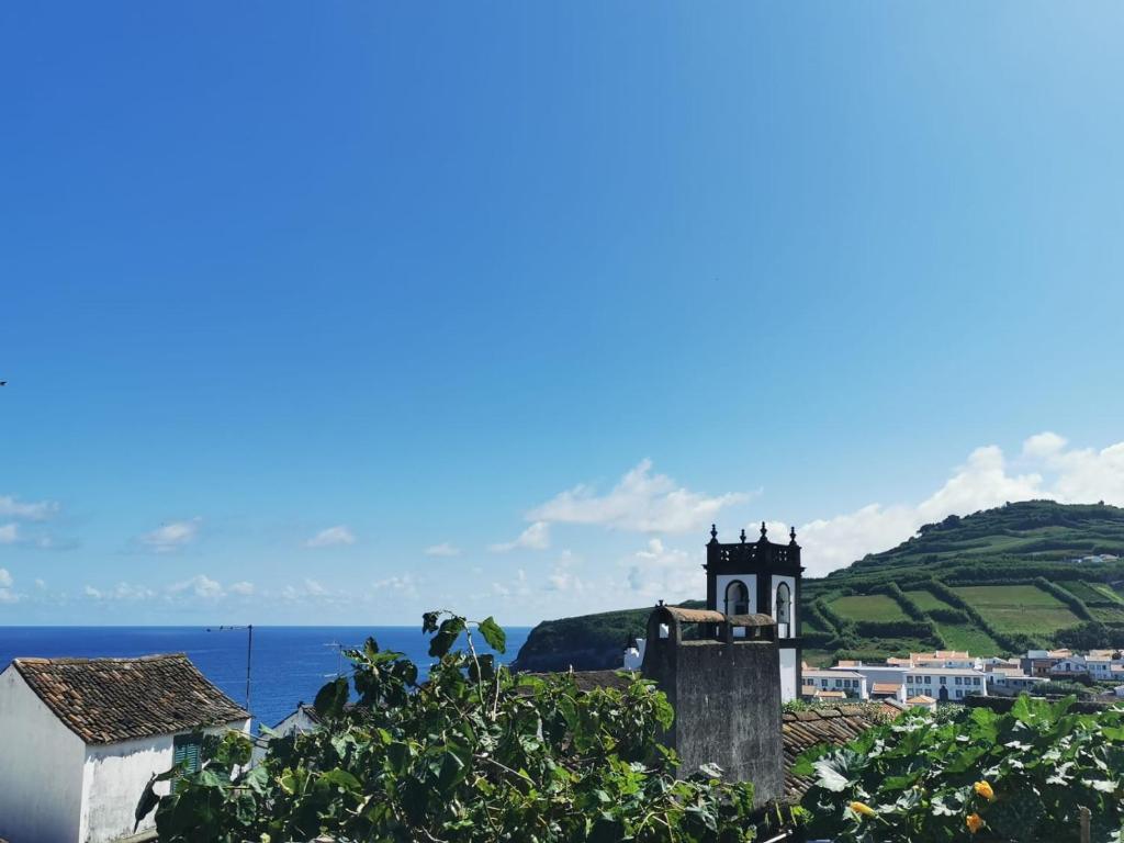 a building with a clock tower next to the ocean at The Handmade House Azores in Porto Formoso
