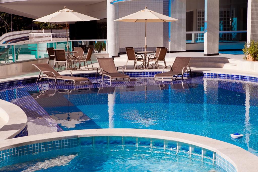 a large swimming pool with chairs and umbrellas at Premier Parc Hotel in Juiz de Fora