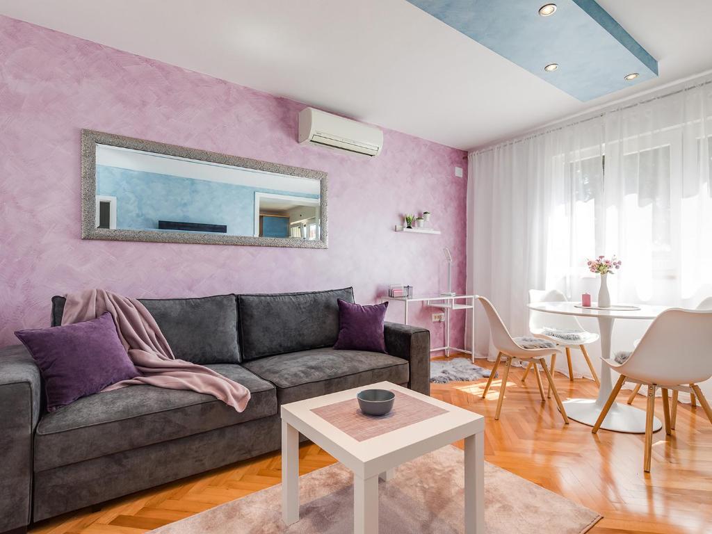ein Wohnzimmer mit einem grauen Sofa und einer rosa Wand in der Unterkunft Porec TWINS Apartment in Poreč