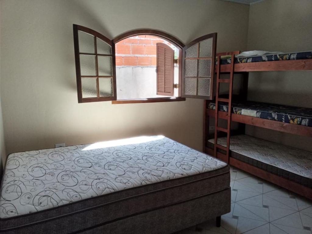 1 dormitorio con 1 cama en una habitación con ventana en Residencial Chalés Lunamar Ubatuba, en Ubatuba