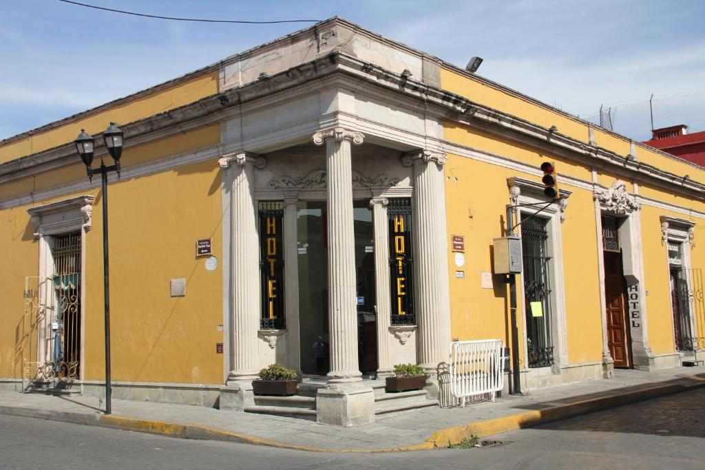 a yellow building with white columns on a street at Hotel Anua Oaxaca in Oaxaca City