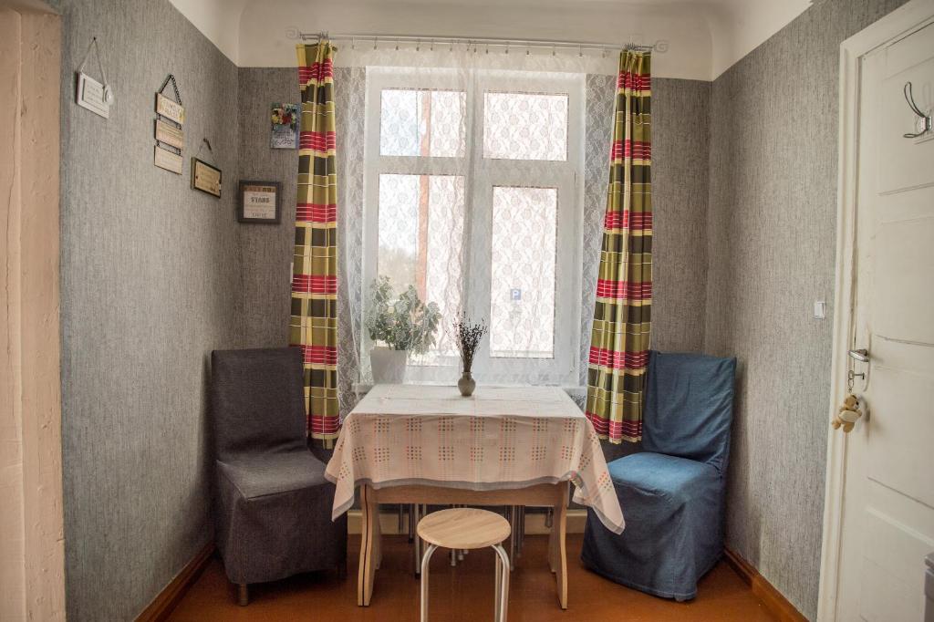 een eetkamer met een tafel en 2 stoelen en een raam bij Timemachine Apartment in Valmiera