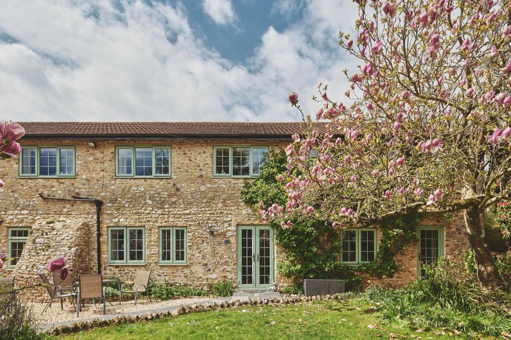 a brick house with a flowering tree in front of it at Millthorn Cottage in Stockland