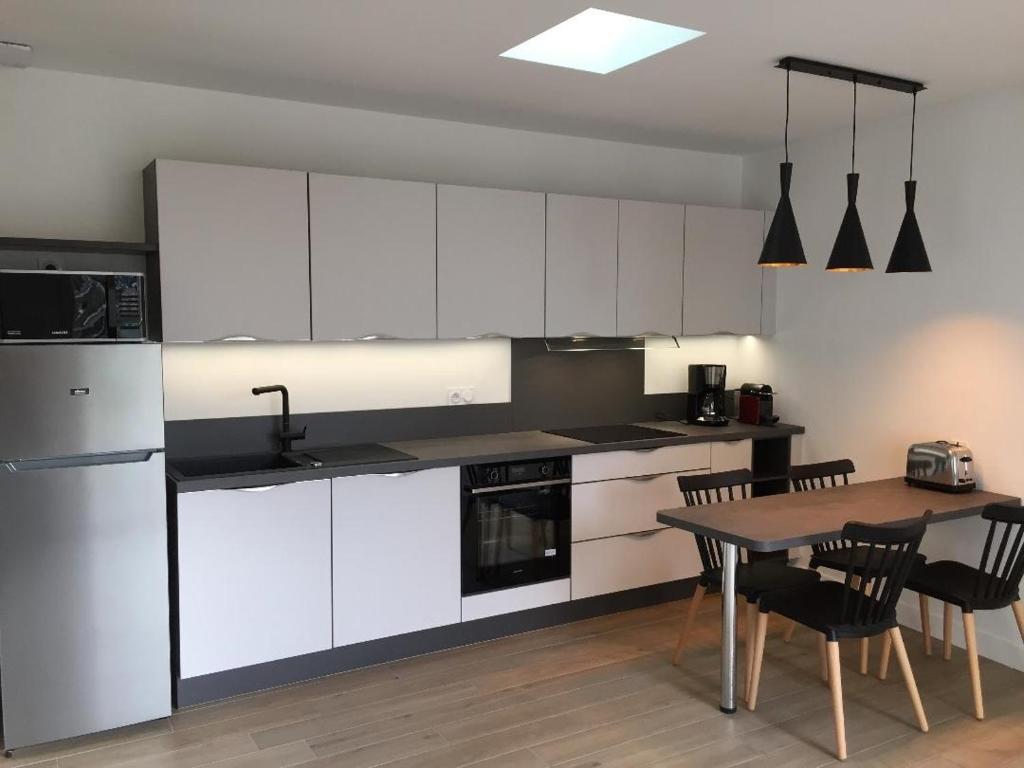 Sweet home في سان ميدارد-أون-جال: مطبخ مع دواليب بيضاء وطاولة مع كراسي