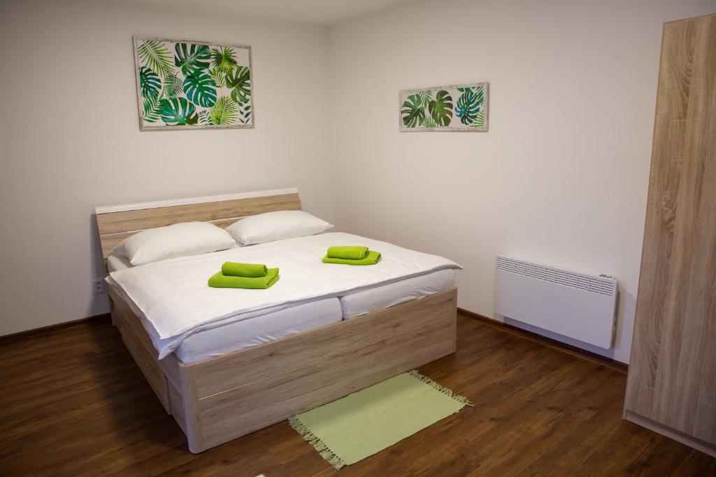 ein Schlafzimmer mit einem Bett mit zwei grünen Handtüchern darauf in der Unterkunft Apartmány AAALIPNO in Lipno nad Vltavou