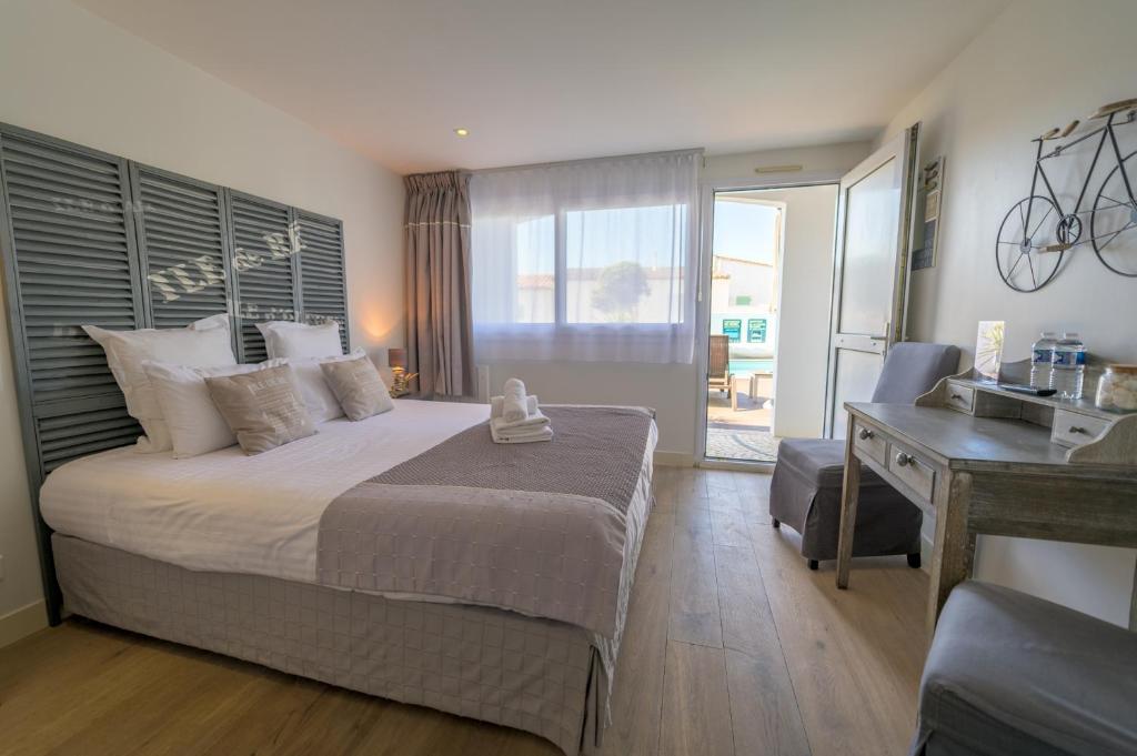 a bedroom with a bed and a desk and a sink at Hôtel Le Peu Breton in Sainte-Marie-de-Ré