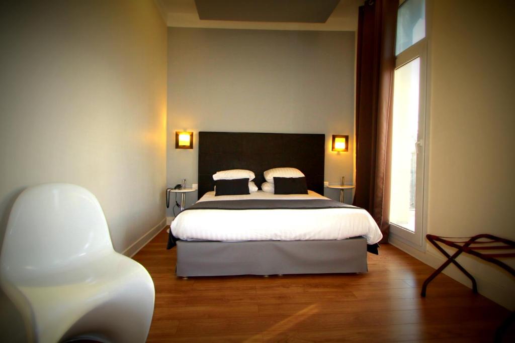 a bedroom with a large bed and a chair at Hôtel Amirauté in Toulon