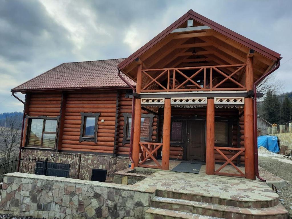 a log cabin with a porch and a stone wall at Карпатский Рай in Yaremche