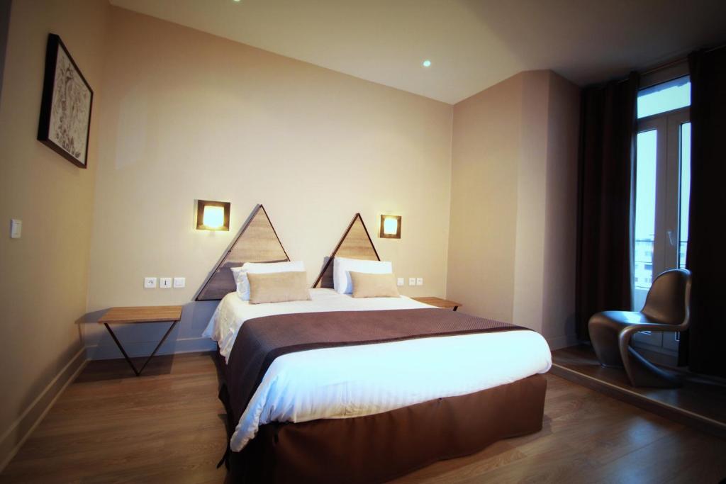 a hotel room with a large bed and a chair at Hôtel Amirauté in Toulon