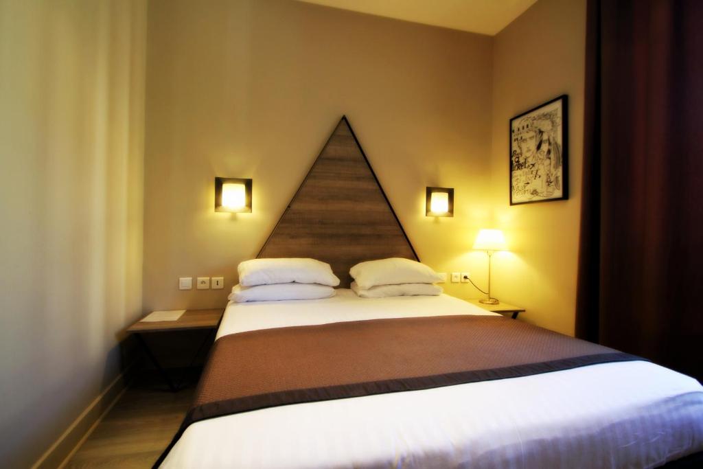 a bedroom with a large bed with two pillows at Hôtel Amirauté in Toulon