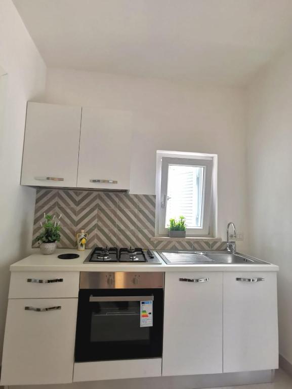 a white kitchen with a stove and a sink at Emidio House in Termini