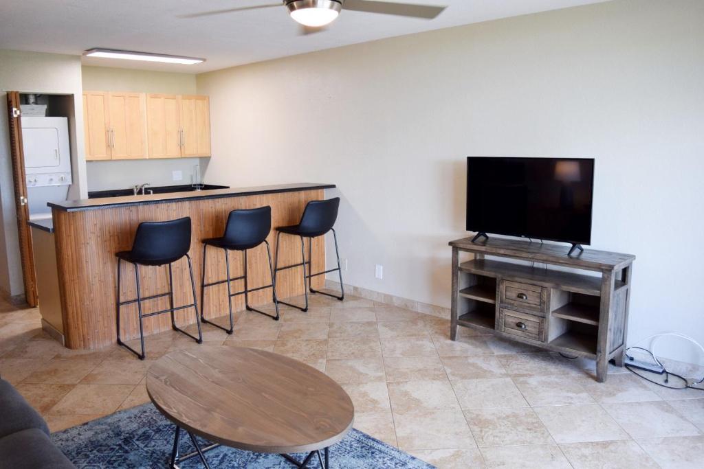 a living room with a bar with stools and a television at Beautiful Private Condo Walking Distance to Beach MV2321 in Kihei