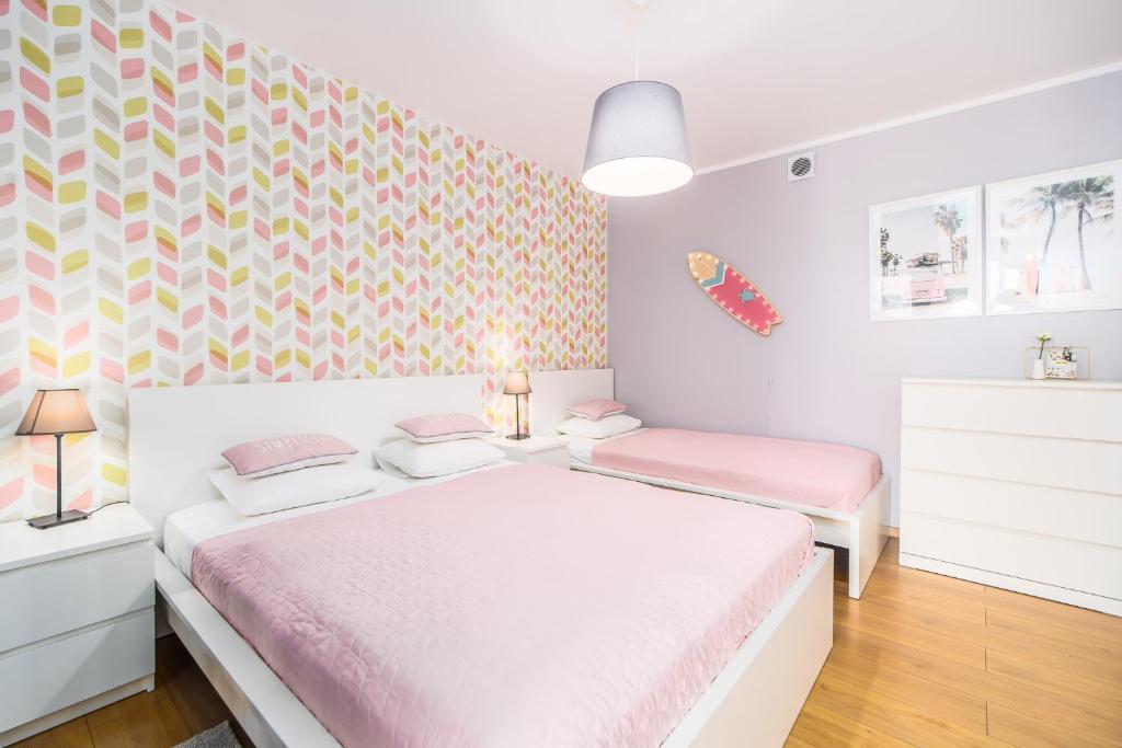 a bedroom with two beds and a colorful wall at Apartamenty Kołobrzeg Osiedle Polanki in Kołobrzeg