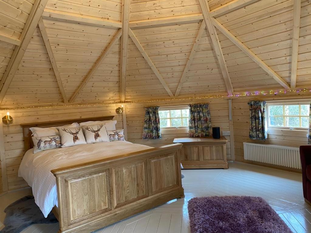 a bedroom with a large bed in a wooden room at Woodland Lodge Oxen Craig in Kintore