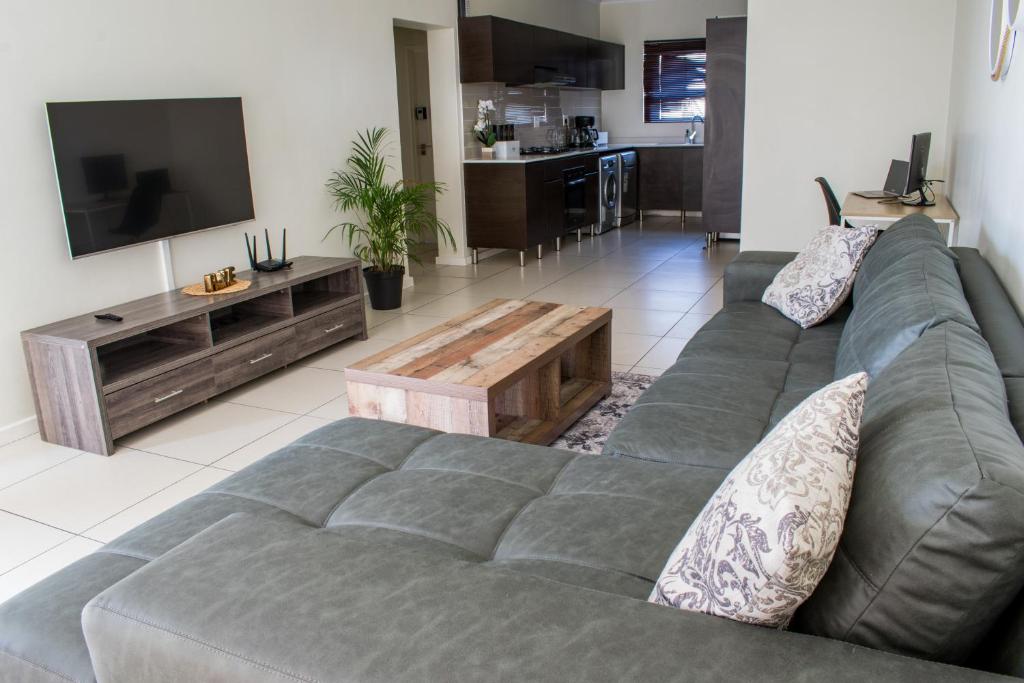 a living room with a gray couch and a tv at Royal Xtian Greenstone Ridge in Johannesburg