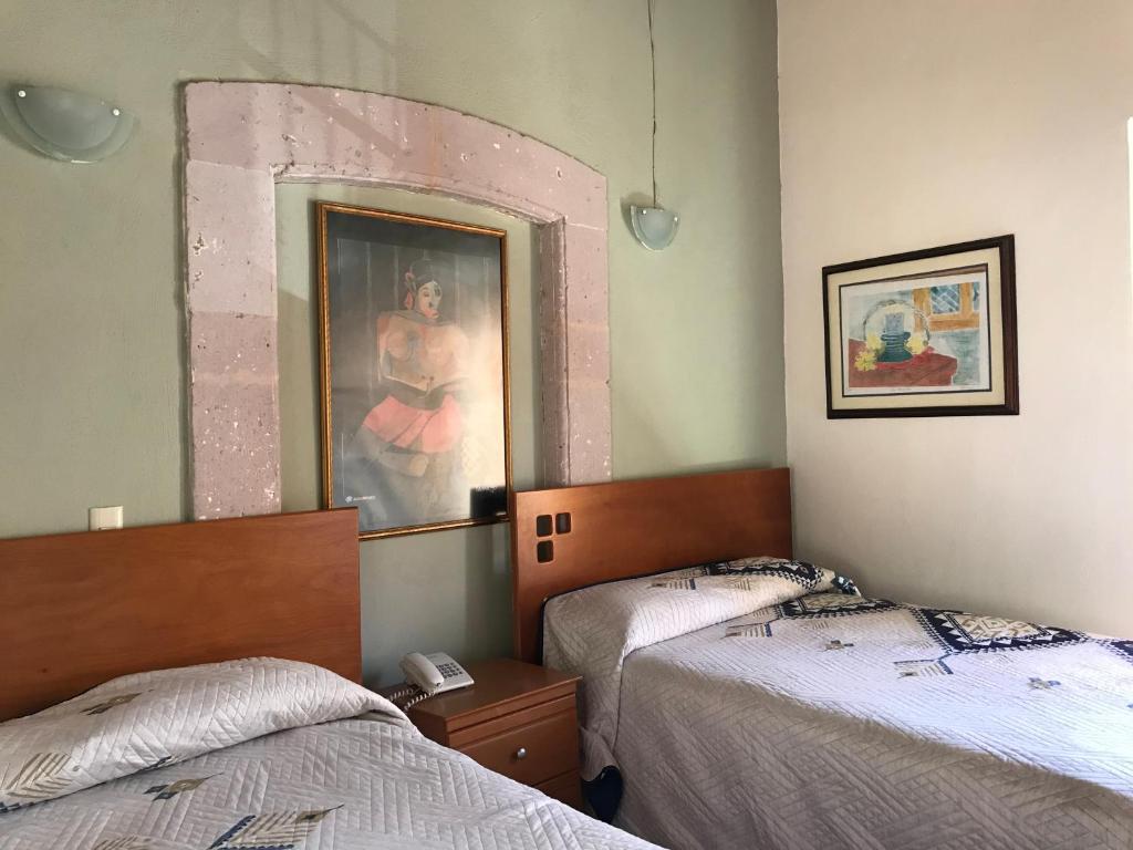 Habitación con 2 camas y una foto en la pared. en Hotel Casa Santo Domingo en Zacatecas