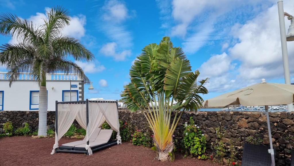 een paar stoelen en een paraplu naast een muur bij Caléndula Beach 1ºLinea mar in Caleta de Sebo