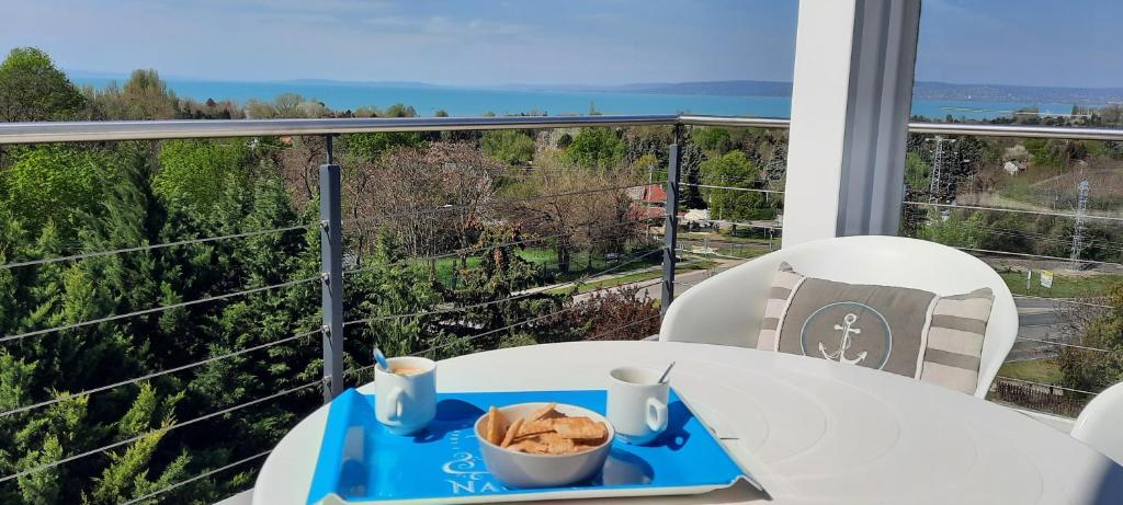 a table with a tray of food on a balcony at Mirador Balaton Panorama Villa & Jacuzzi in Balatonakarattya