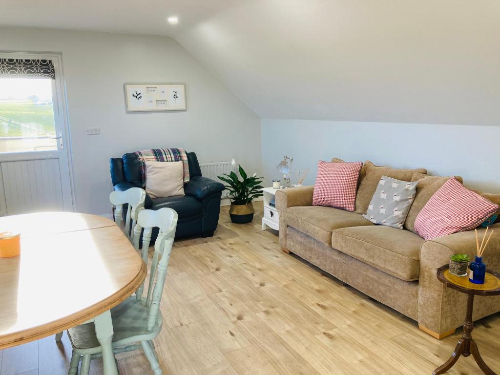 sala de estar con sofá, mesa y sillas en The Loft at Number 84, en Ballymena