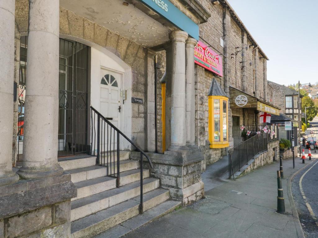 a stone building with a white door on a street at Palace Apartment Main Street in Grange Over Sands