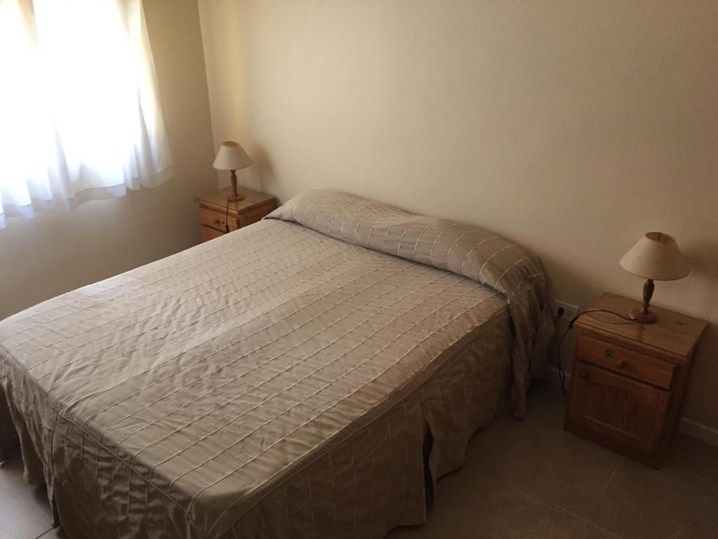 Miramar - Depto 2 ambientes في ميرامار: غرفة نوم صغيرة بها سرير ومداخلة ليلتين