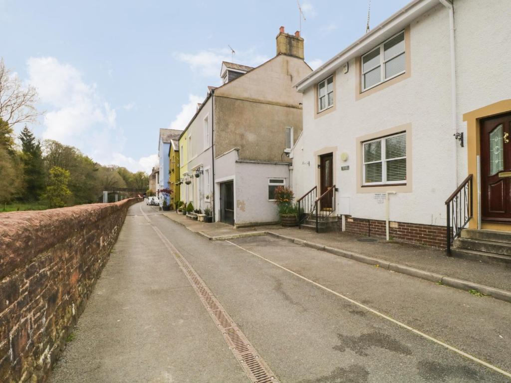 eine leere Straße mit Häusern und einer Mauer in der Unterkunft Riverside Cottage in Cockermouth