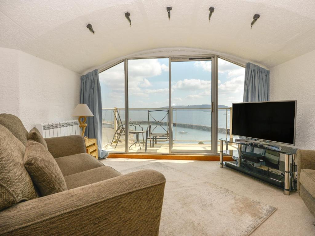 a living room with a television and a large window at Cannons Folly in Torpoint