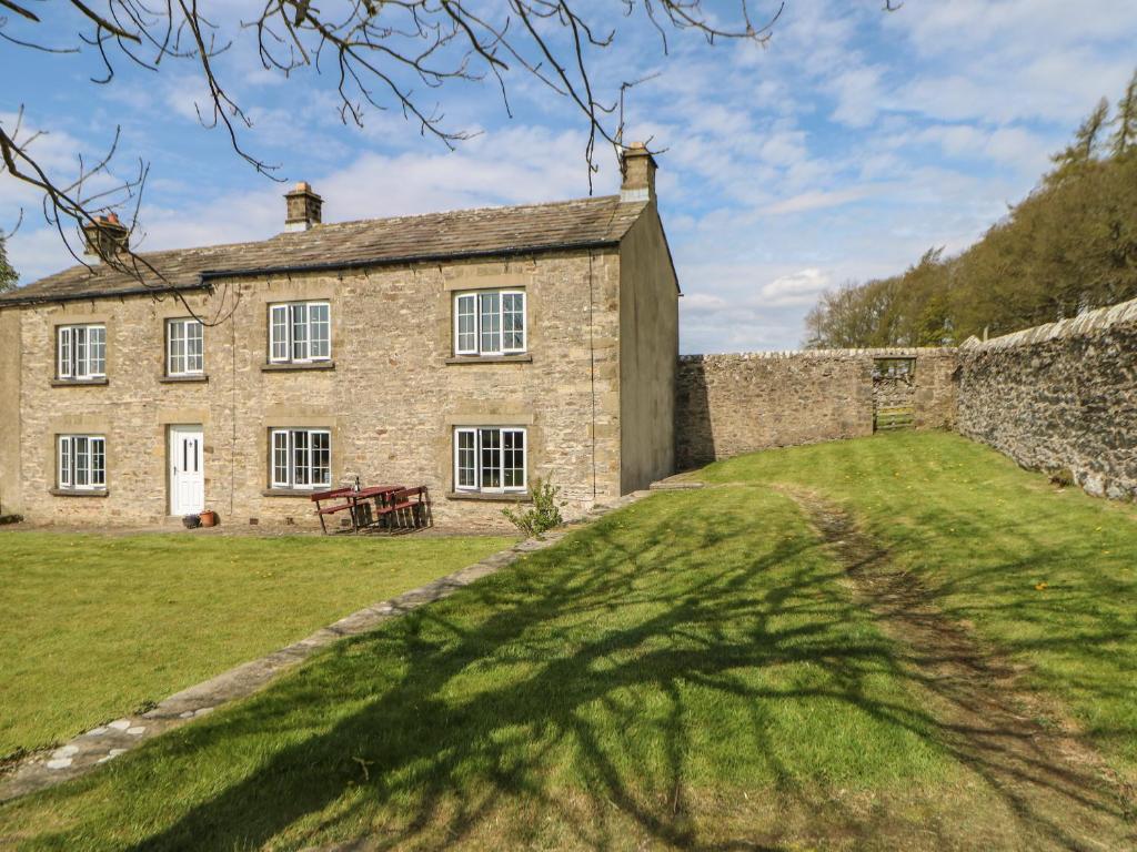 an old stone house with a large shadow of a tree at Sunnyside Cottage in Stainton