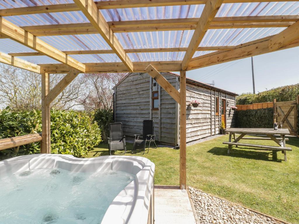 a hot tub under a wooden pergola in a yard at Cherry Lodge in Watchet