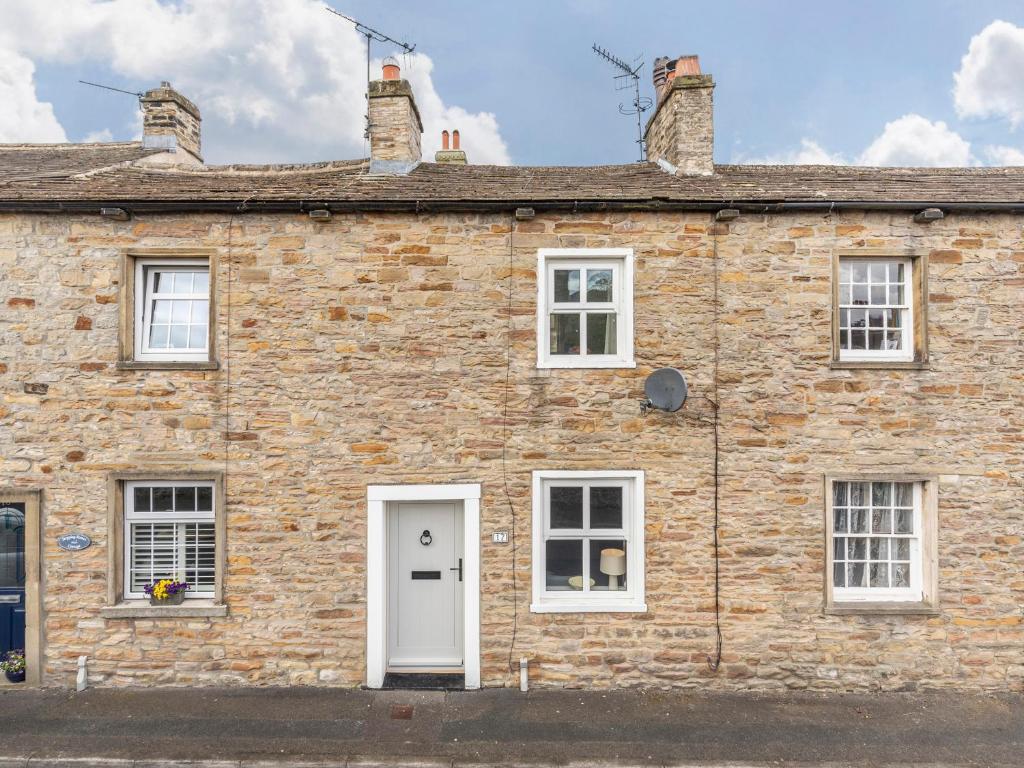 an old brick house with a white door and windows at Riverstone Cottage in Skipton