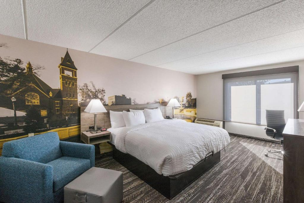 a hotel room with a bed and a chair at Clarion Pointe Near University in Rock Hill