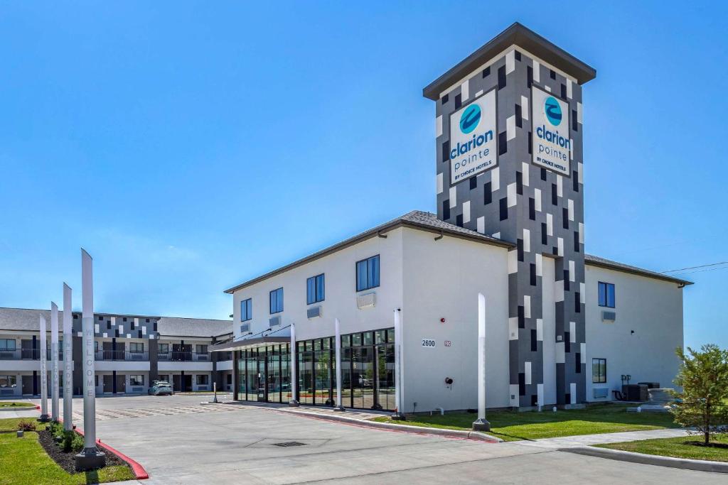 un edificio con una torre de reloj en un aparcamiento en Clarion Pointe Port Arthur-Beaumont South, en Port Arthur