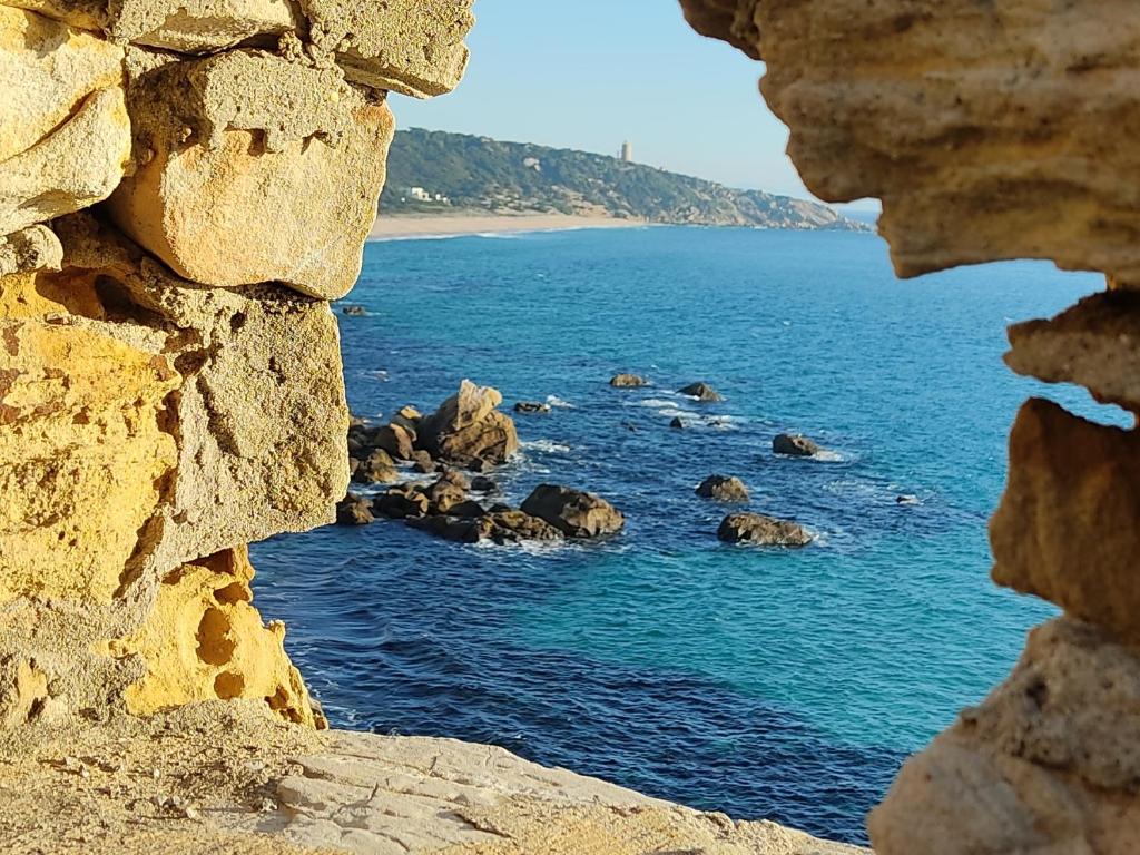 a view of the ocean through a rock window at Apartamentos Bolonia - M a n u e l a in Bolonia