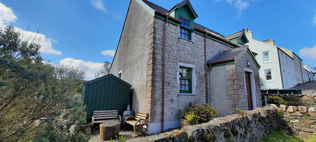 uma casa de tijolos com um banco à frente em Strome Beag em Tobermory
