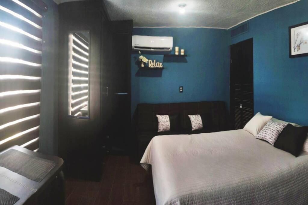 a bedroom with a bed and a blue wall at Estudio Ejec Independiente en ambiente Familiar in Chihuahua