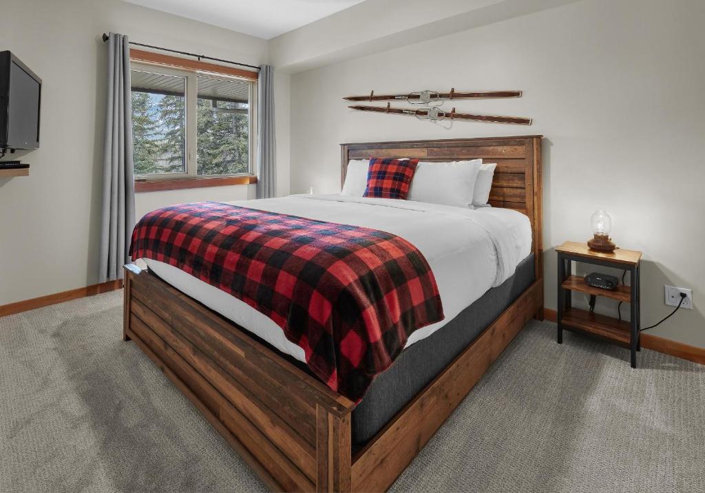 a bedroom with a large bed with a plaid blanket at Newly Renovated Grizzly Lodge, Spacious 3BR 2BA with open pool, hot tub in Canmore