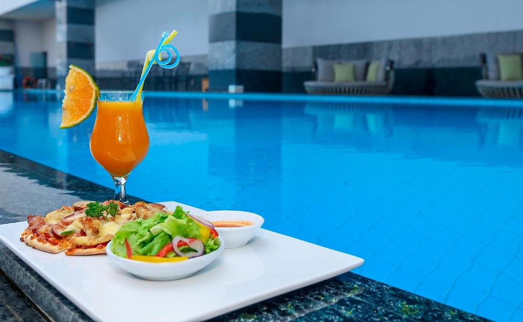 A plated pizza-and-salad meal with a cocktail beside the swimming pool.