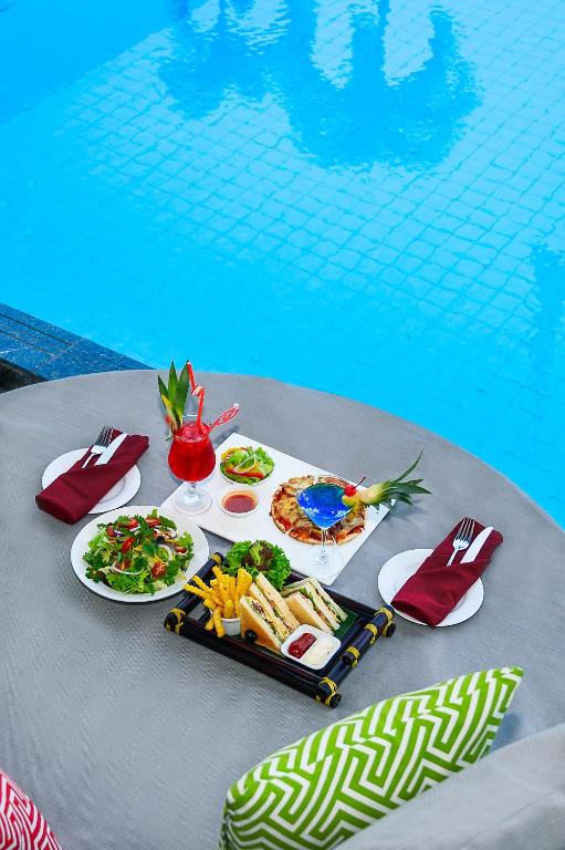 Poolside dining set with plated food and a patterned lounge cushion.