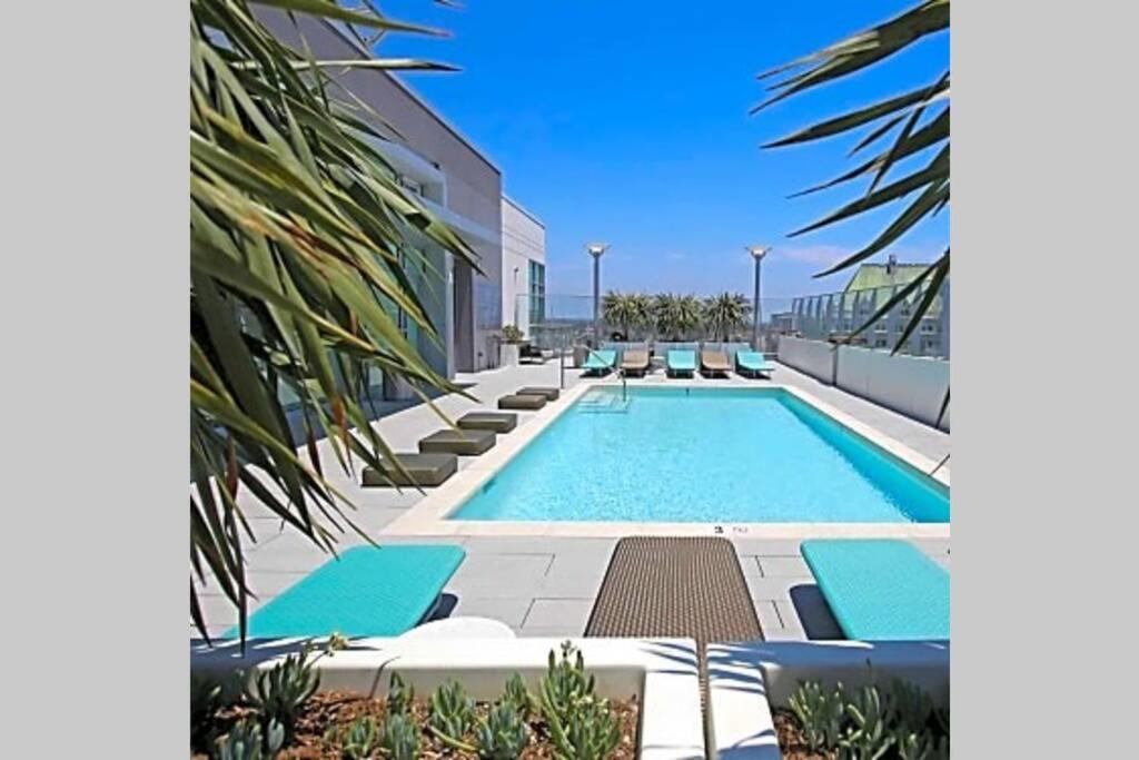 a swimming pool with blue lounge chairs next to a building at Luxury Highrise Living Downtown LA in Los Angeles