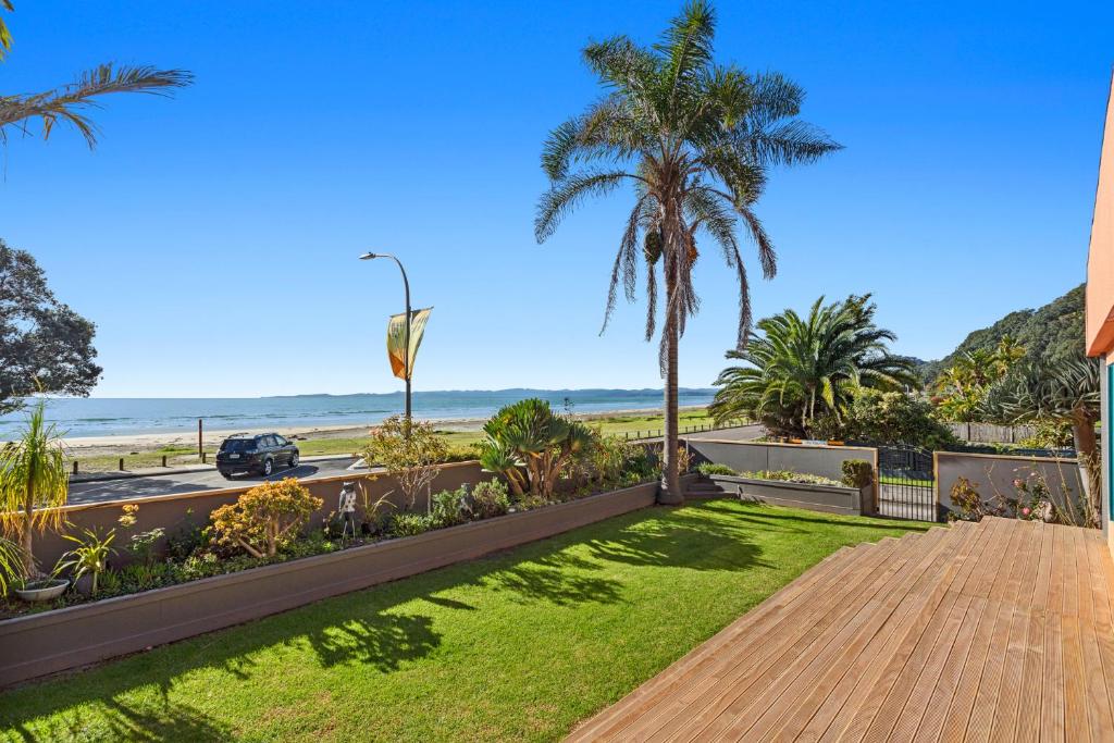 a wooden walkway to the beach with palm trees at The Lights House - Beachfront Ohope Holiday Home in Ohope Beach