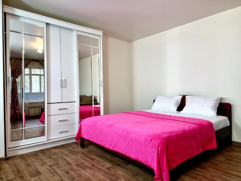 モスクワにあるApartamenty RoomOnDay Beringov 4のピンクベッド1台と鏡付きのベッドルーム1室