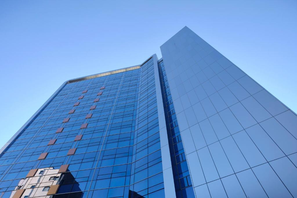 un grand bâtiment en verre avec un ciel bleu en arrière-plan dans l'établissement S Stay Hotel, à Suwon